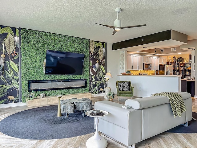 6336 Buford St Unit 207, Orlando, FL 32835 - living room featuring a ceiling fan, a textured ceiling, and a glass covered fireplace