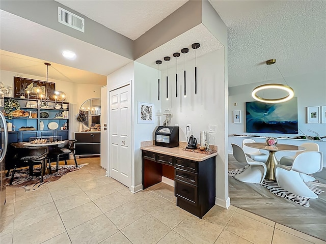 6336 Buford St Unit 207, Orlando, FL 32835 - kitchen with a chandelier, dark brown cabinets, light tile patterned floors, light countertops, and hanging light fixtures