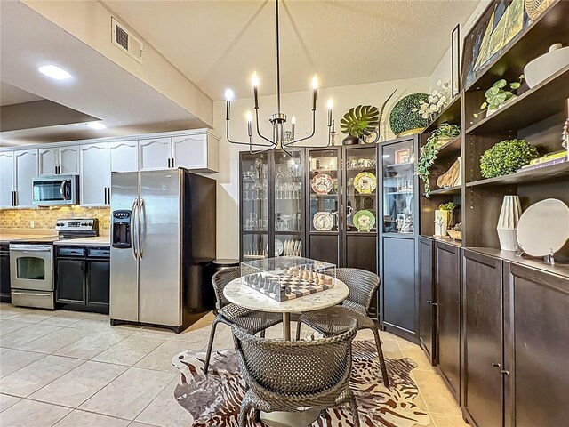 6336 Buford St Unit 207, Orlando, FL 32835 - kitchen featuring stainless steel appliances, light tile patterned floors, a chandelier, backsplash, and white cabinets