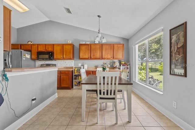 36646 Oconee Ave, Eustis, FL 32736 - kitchen with black microwave, stainless steel fridge, lofted ceiling, brown cabinets, and a chandelier