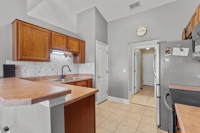 36646 Oconee Ave, Eustis, FL 32736 - kitchen with a sink, a peninsula, light tile patterned flooring, tasteful backsplash, and brown cabinets