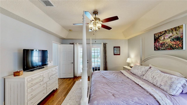 14723 Pine Cone Trl, Clermont, FL 34711 - bedroom featuring wood finished floors, ceiling fan, a tray ceiling, and a textured ceiling