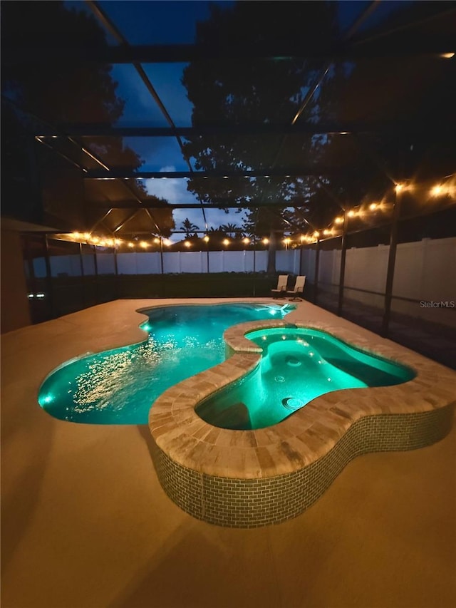 14723 Pine Cone Trl, Clermont, FL 34711 - pool at night with a patio, glass enclosure, and a pool with connected hot tub
