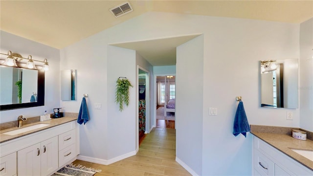 14723 Pine Cone Trl, Clermont, FL 34711 - bathroom with wood finished floors, two vanities, ensuite bath, and lofted ceiling