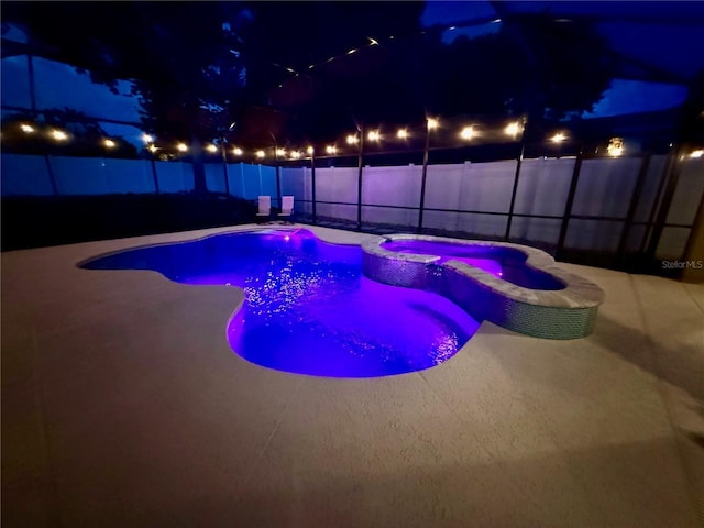 14723 Pine Cone Trl, Clermont, FL 34711 - pool at twilight with a fenced backyard, a patio area, glass enclosure, and a pool with connected hot tub