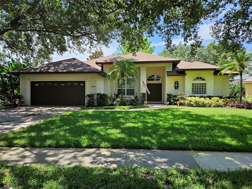 9491 Wickham Way, Orlando, FL 32836 - ranch-style home featuring an attached garage, a front lawn, concrete driveway, and stucco siding