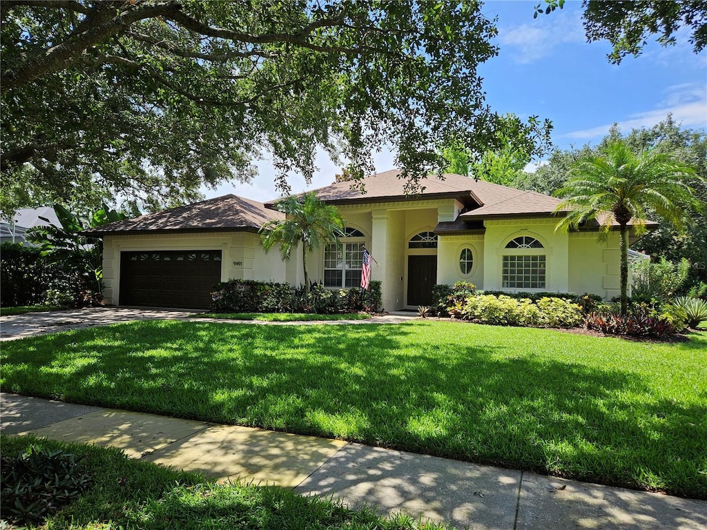 9491 Wickham Way, Orlando, FL 32836 - single story home with an attached garage, concrete driveway, a front lawn, and stucco siding