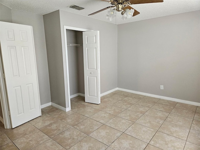 304 Lake Daisy Loop, Winter Haven, FL 33884 - unfurnished bedroom featuring a textured ceiling, light tile patterned flooring, a closet, ceiling fan, and baseboards