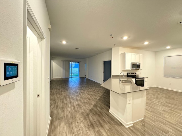 1147 Pomelo St, Davenport, FL 33837 - kitchen with appliances with stainless steel finishes, a sink, light wood finished floors, baseboards, and white cabinetry