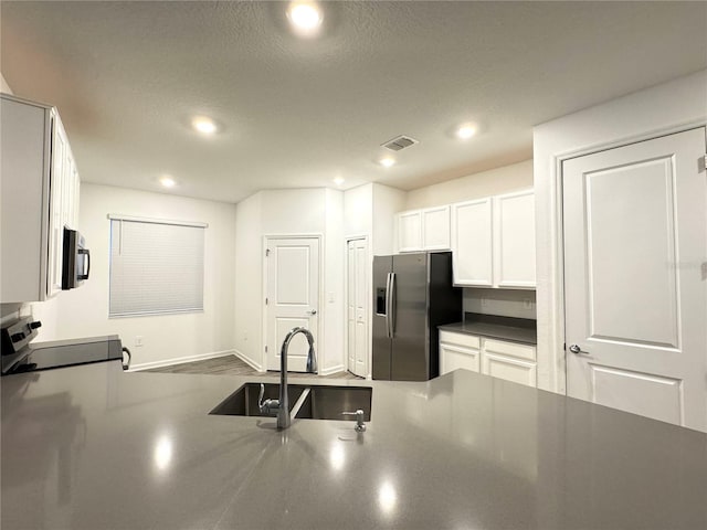 1147 Pomelo St, Davenport, FL 33837 - kitchen featuring stainless steel appliances, a sink, white cabinets, dark countertops, and recessed lighting