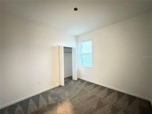 1147 Pomelo St, Davenport, FL 33837 - unfurnished bedroom featuring dark colored carpet, baseboards, and a closet