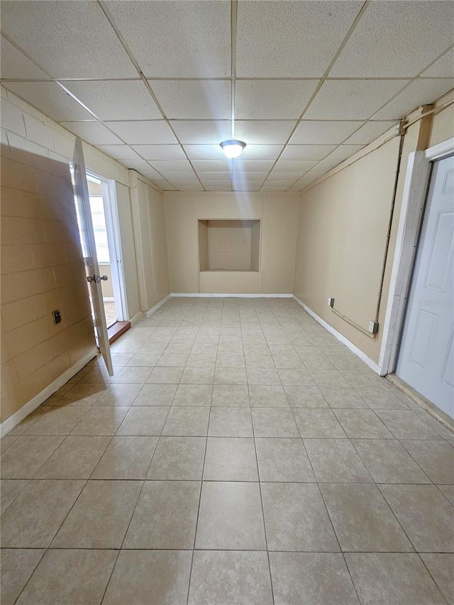 unfurnished room with a drop ceiling, light tile patterned floors, and baseboards