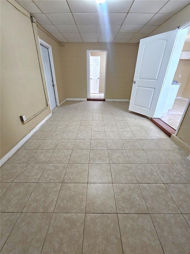 spare room with a drop ceiling, light tile patterned floors, and baseboards