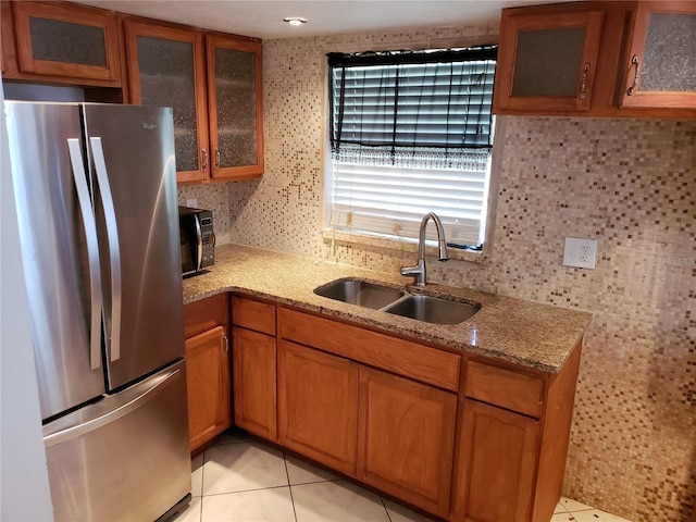 1000 S Semoran Blvd Unit 415, Winter Park, FL 32792 - kitchen featuring freestanding refrigerator, a sink, brown cabinets, light stone counters, and glass insert cabinets
