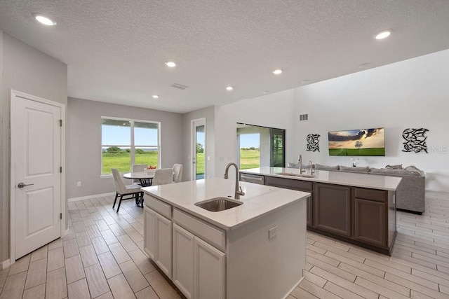 1551 Gateway Ln, Kissimmee, FL 34746 - kitchen featuring a kitchen island with sink, light countertops, open floor plan, wood tiled floors, and a textured ceiling