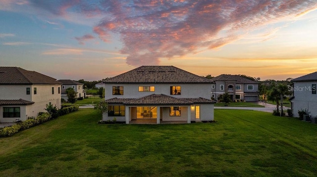1551 Gateway Ln, Kissimmee, FL 34746 - back of property at dusk featuring stucco siding, a lawn, and a tiled roof