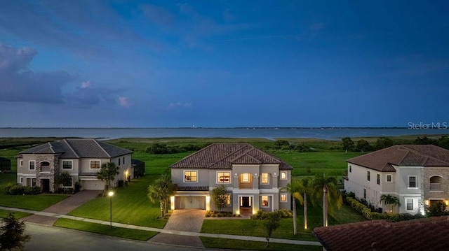 1551 Gateway Ln, Kissimmee, FL 34746 - view of front of house featuring driveway, a front lawn, a water view, stucco siding, and a garage