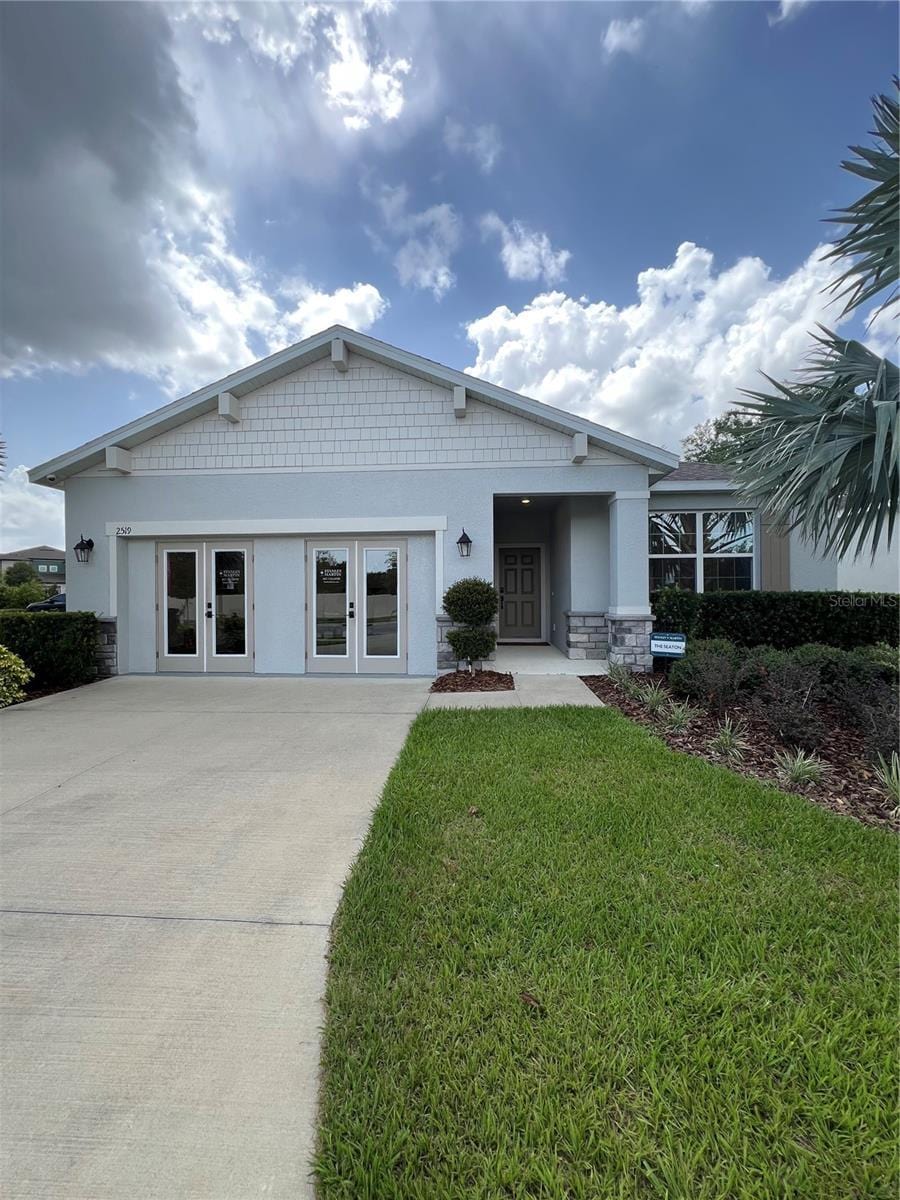 2519 Avalon Park Blvd, Tavares, FL 32778 - view of front of property with concrete driveway, a front lawn, stucco siding, french doors, and stone siding