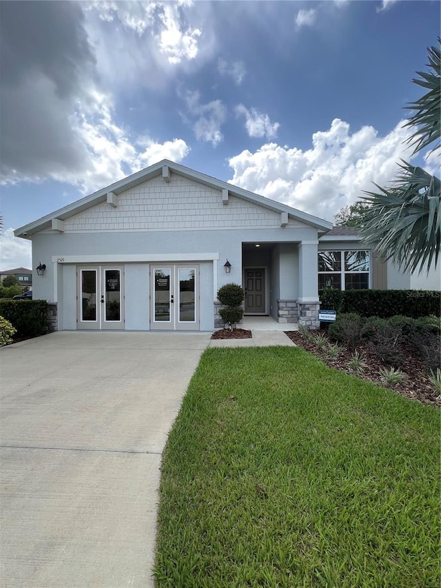 2519 Avalon Park Blvd, Tavares, FL 32778 - view of front of property with concrete driveway, a front lawn, stucco siding, french doors, and stone siding