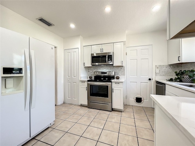 249 Spartan Dr, Maitland, FL 32751 - kitchen featuring appliances with stainless steel finishes, light countertops, decorative backsplash, white cabinets, and light tile patterned floors