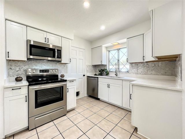 249 Spartan Dr, Maitland, FL 32751 - kitchen featuring appliances with stainless steel finishes, a textured ceiling, light countertops, white cabinets, and tasteful backsplash