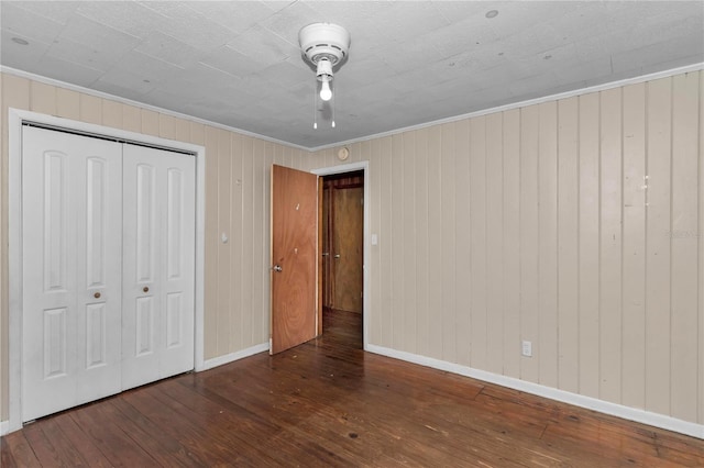 1753 NW 44th St, Ocala, FL 34475 - unfurnished bedroom featuring wood-type flooring, baseboards, crown molding, a closet, and wood walls