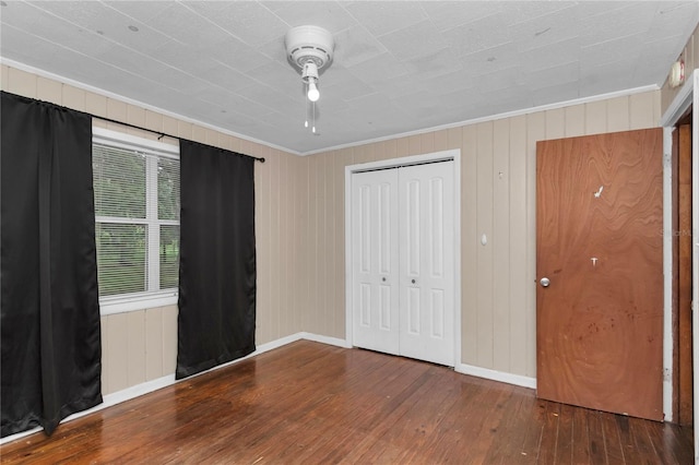 1753 NW 44th St, Ocala, FL 34475 - unfurnished bedroom featuring hardwood / wood-style flooring, crown molding, a closet, baseboards, and wooden walls