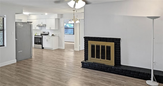 2804 Clearfield Ave, Orlando, FL 32808 - unfurnished living room featuring ceiling fan, light wood finished floors, a chandelier, and a brick fireplace