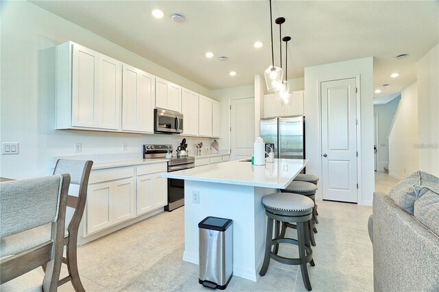 832 Longboat Dr, Davenport, FL 33896 - kitchen featuring appliances with stainless steel finishes, a kitchen bar, white cabinetry, an island with sink, and light countertops