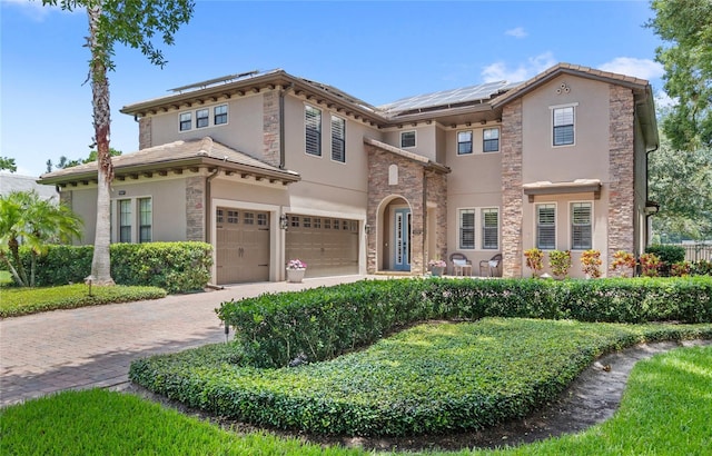 25537 High Hampton Cir, Sorrento, FL 32776 - view of front of house with stucco siding, stone siding, a garage, and solar panels