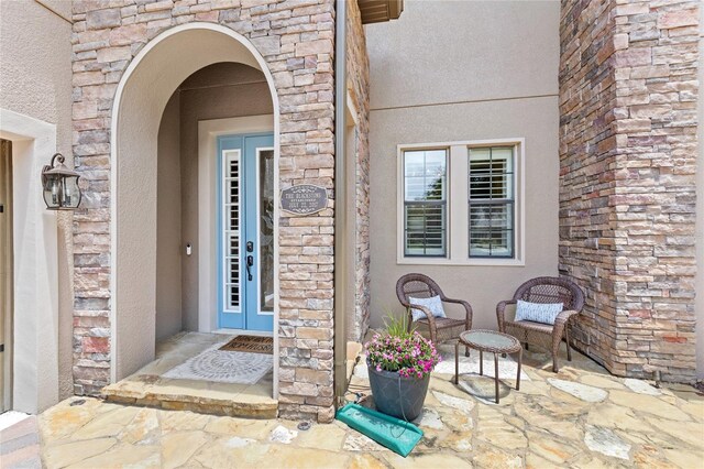 25537 High Hampton Cir, Sorrento, FL 32776 - view of exterior entry featuring stone siding, stucco siding, and a patio area
