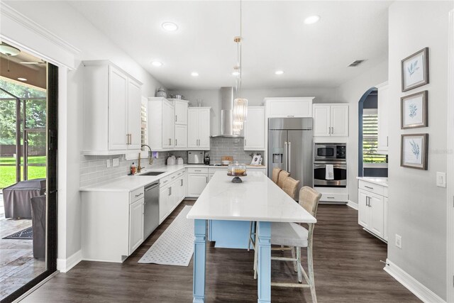 25537 High Hampton Cir, Sorrento, FL 32776 - kitchen featuring stainless steel appliances, wall chimney range hood, a sink, backsplash, and white cabinetry