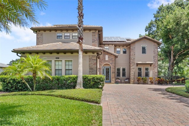 25537 High Hampton Cir, Sorrento, FL 32776 - view of front of property with stucco siding, roof mounted solar panels, stone siding, a front yard, and a tiled roof