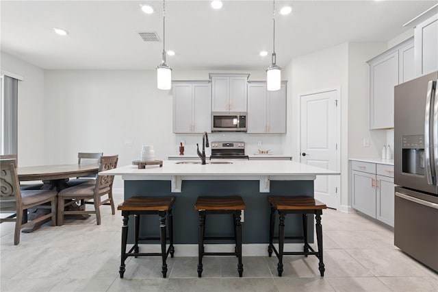 2279 Mountain Pine St, Ocoee, FL 34761 - kitchen featuring stainless steel appliances, gray cabinetry, light countertops, a breakfast bar, and a kitchen island with sink