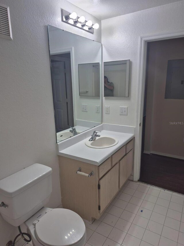 5459 Vineland Rd Unit 4310, Orlando, FL 32811 - half bathroom with vanity, toilet, tile patterned flooring, electric panel, and a textured wall