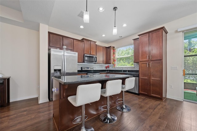 3508 Brighton Park Cir, Belle Isle, FL 32812 - kitchen with appliances with stainless steel finishes, dark countertops, dark wood finished floors, a center island, and backsplash