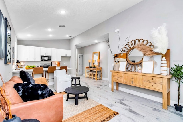23430 SW Neptune Blvd, Dunnellon, FL 34431 - living area featuring vaulted ceiling, light wood-type flooring, baseboards, a textured ceiling, and recessed lighting