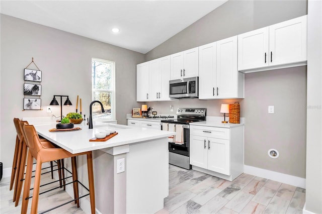 23430 SW Neptune Blvd, Dunnellon, FL 34431 - kitchen with stainless steel appliances, a sink, a kitchen breakfast bar, white cabinetry, and light countertops