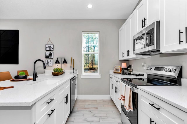 23430 SW Neptune Blvd, Dunnellon, FL 34431 - kitchen featuring stainless steel appliances, a sink, a peninsula, light marble finish flooring, and baseboards