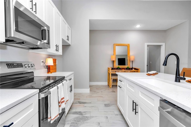 23430 SW Neptune Blvd, Dunnellon, FL 34431 - kitchen with appliances with stainless steel finishes, a sink, white cabinetry, recessed lighting, and light stone counters