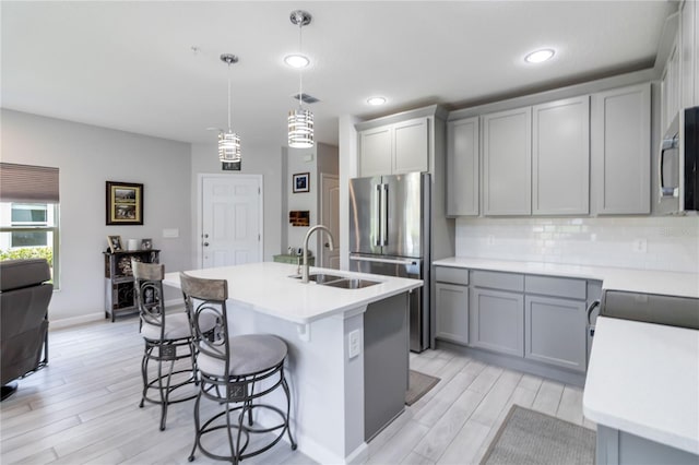 378 Cape Honeysuckle Pl, Sanford, FL 32771 - kitchen featuring gray cabinets, stainless steel appliances, light wood-type flooring, a breakfast bar area, and light countertops