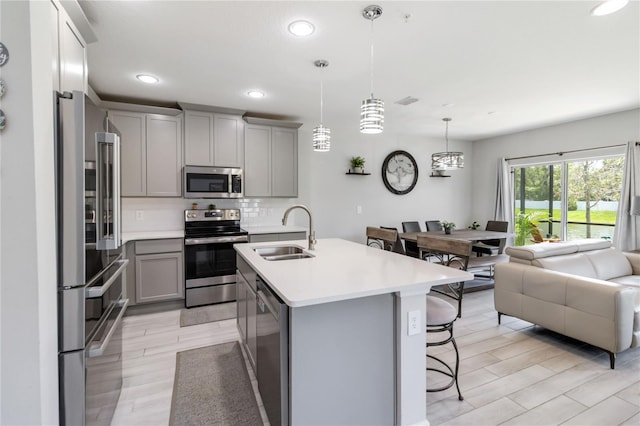 378 Cape Honeysuckle Pl, Sanford, FL 32771 - kitchen featuring appliances with stainless steel finishes, gray cabinets, a breakfast bar, light countertops, and open floor plan