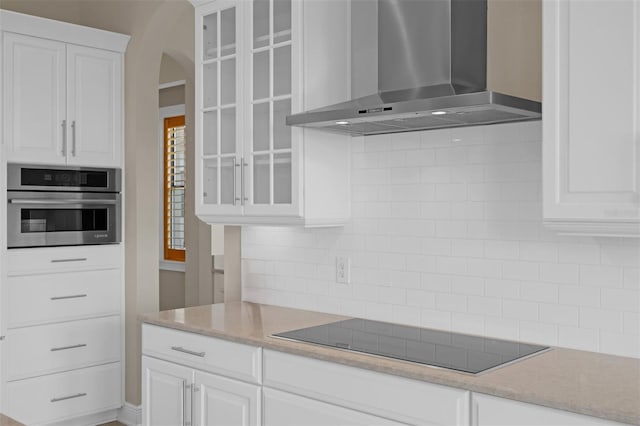 15344 Johns Lake Pointe Blvd, Winter Garden, FL 34787 - kitchen featuring wall chimney range hood, black electric cooktop, tasteful backsplash, and glass insert cabinets
