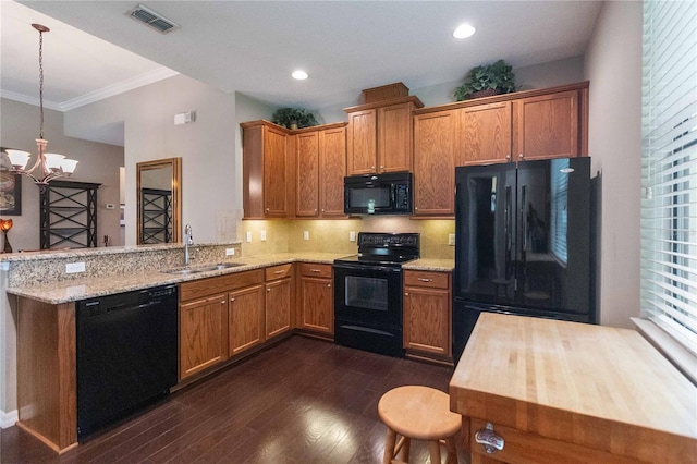 3637 Foxchase Dr, Clermont, FL 34711 - kitchen featuring black appliances, dark wood-type flooring, a peninsula, backsplash, and crown molding