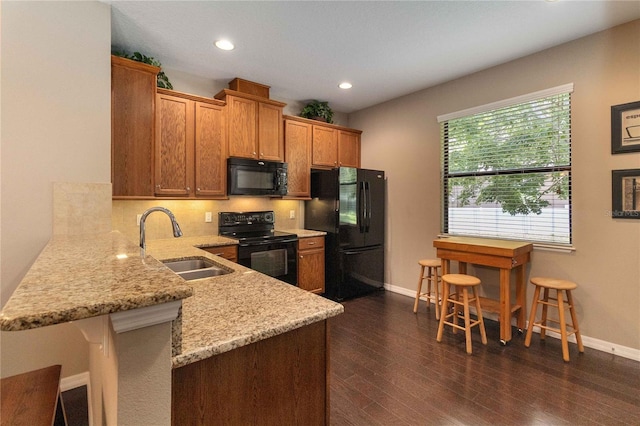 3637 Foxchase Dr, Clermont, FL 34711 - kitchen with black appliances, a peninsula, light stone countertops, brown cabinets, and tasteful backsplash