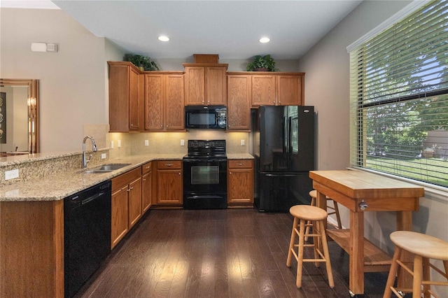 3637 Foxchase Dr, Clermont, FL 34711 - kitchen with black appliances, dark wood finished floors, light stone countertops, decorative backsplash, and a peninsula