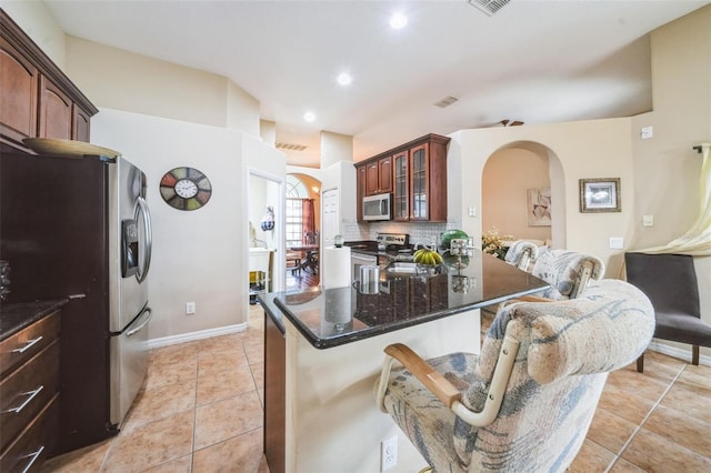 742 Seneca Trl, Saint Cloud, FL 34772 - kitchen with stainless steel appliances, arched walkways, glass insert cabinets, tasteful backsplash, and light tile patterned floors