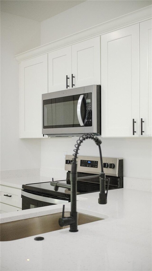 2498 W Magenta Dr, Citrus Springs, FL 34434 - kitchen view of stainless steel microwave, white cabinetry, and light stone counters