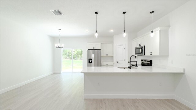 2498 W Magenta Dr, Citrus Springs, FL 34434 - kitchen featuring appliances with stainless steel finishes, light countertops, light wood-style floors, a chandelier, and white cabinetry