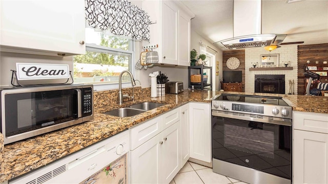 5177 Chesapeake Ave, Orlando, FL 32808 - kitchen with appliances with stainless steel finishes, island exhaust hood, white cabinets, light tile patterned floors, and stone countertops
